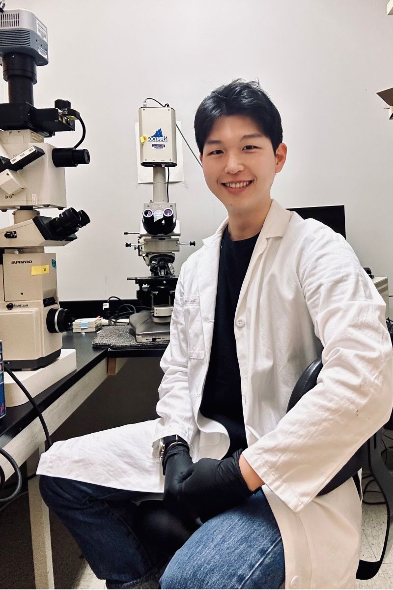 Joe Lim at microscope in lab